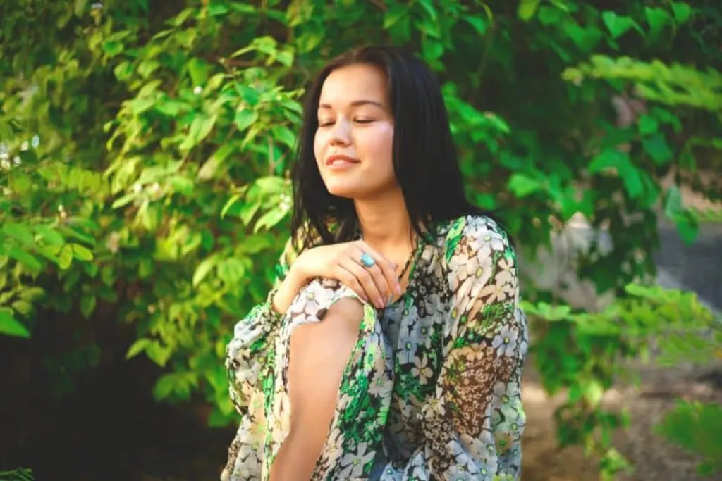 por trait of a beautiful smiling brunette on a background of greenery.