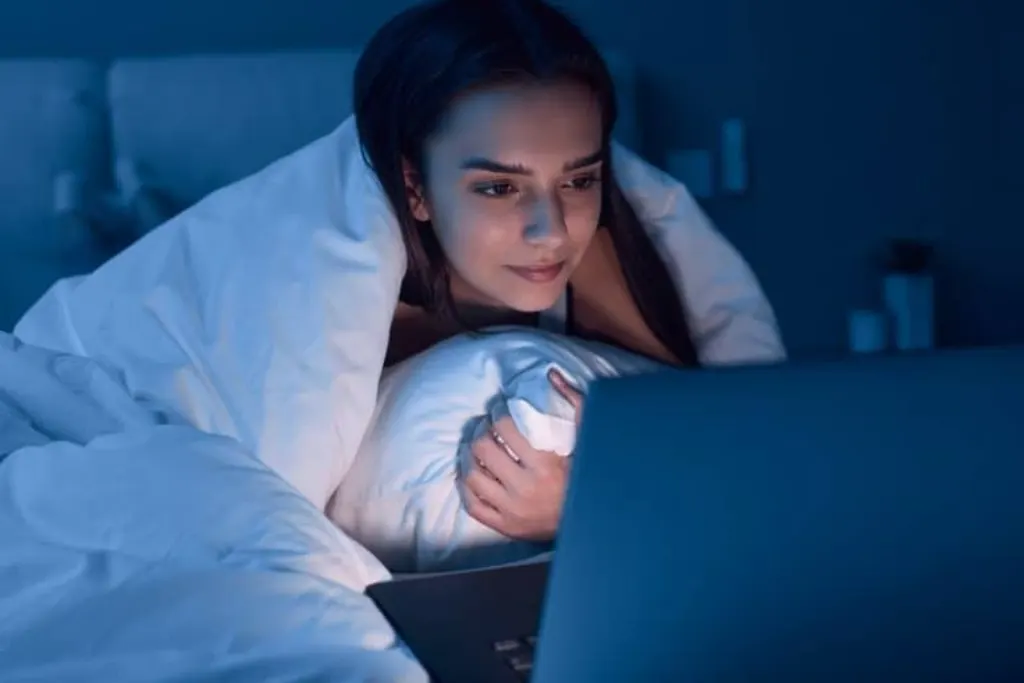Woman watching movie in bed at night