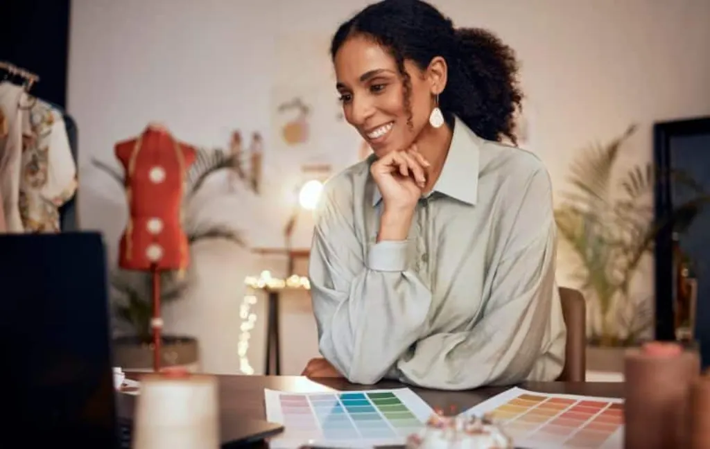 Ecommerce, smile and fashion, black woman designer in creative studio for clothing manufacturing an